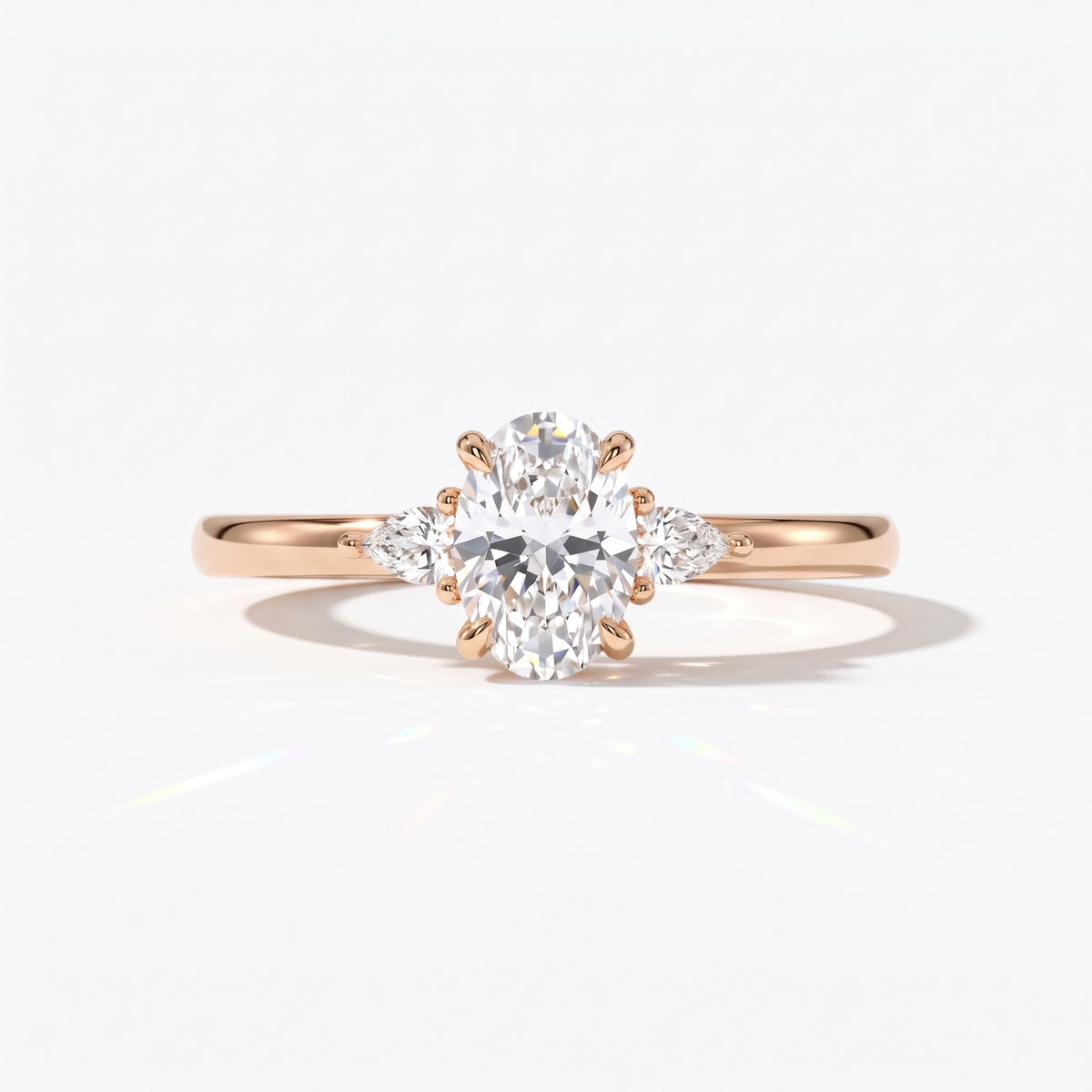 Oval cut lab-grown diamond three-stone engagement ring with pear side stones in 14K (585) rose gold, front view
