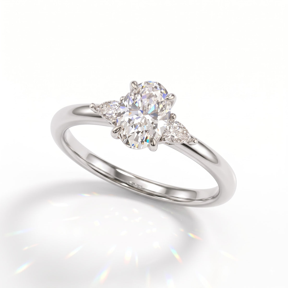 Oval cut lab-grown diamond three-stone engagement ring with pear side stones in 950 platinum, angled view
