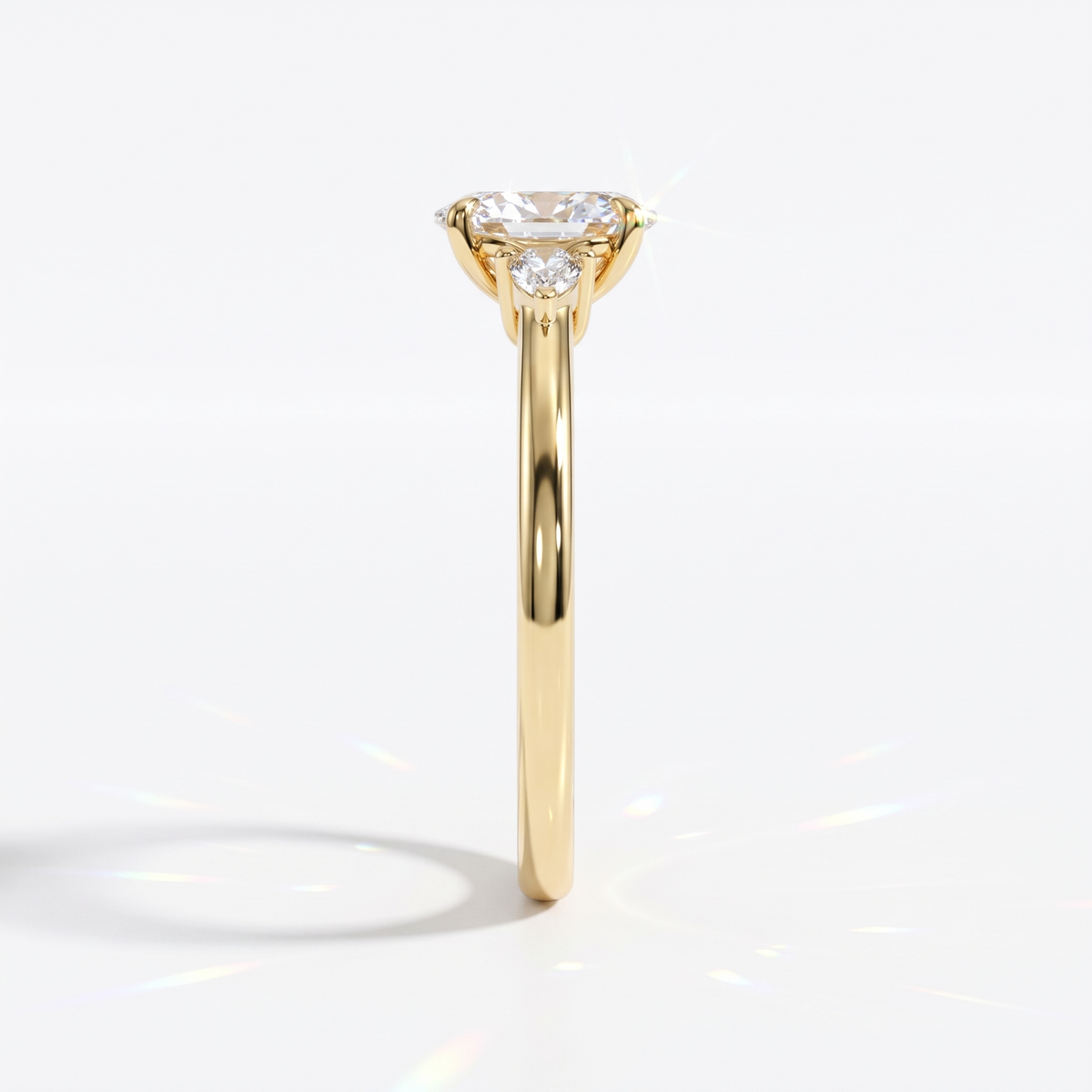 Oval cut lab-grown diamond three-stone engagement ring with pear side stones in 14K (585) yellow gold, side view