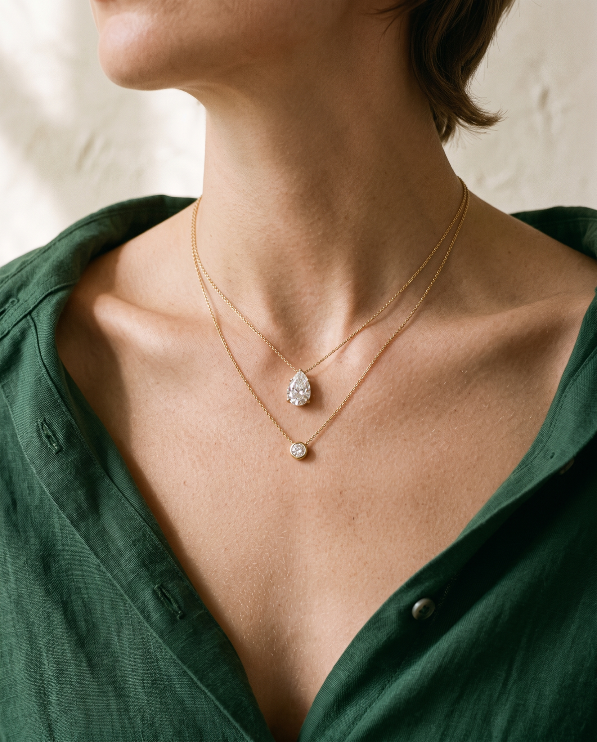 Layered yellow gold necklaces with pear and round lab-grown diamond pendants by BEUSÉA