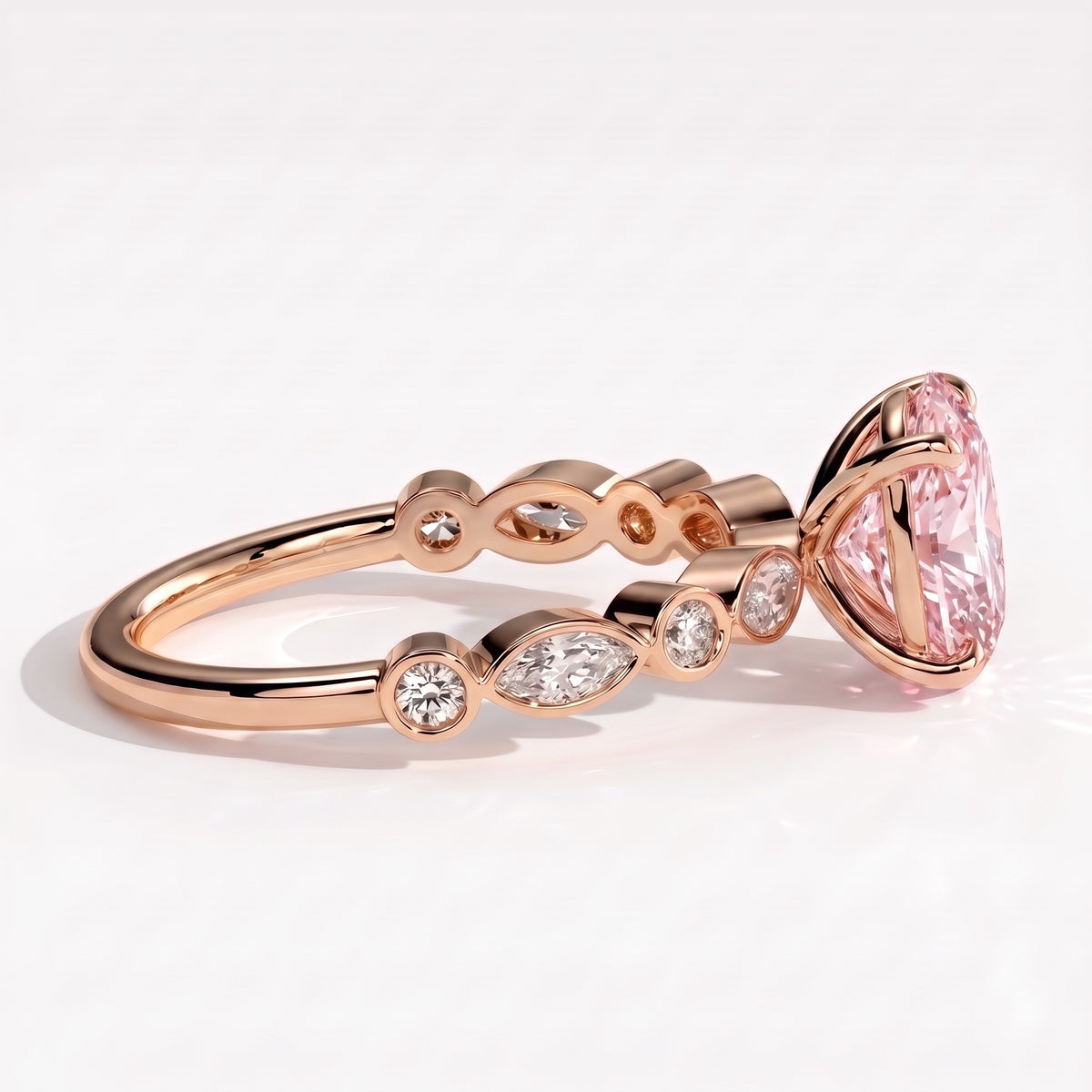 Fancy Vivid Pink oval lab-grown diamond engagement ring with bezel-set pear and round shoulder accents in 18K (750) rose gold, detail view of the bezel-set shoulder accents