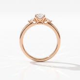 Oval cut lab-grown diamond three-stone engagement ring with pear side stones in 14K (585) rose gold, upright profile view 