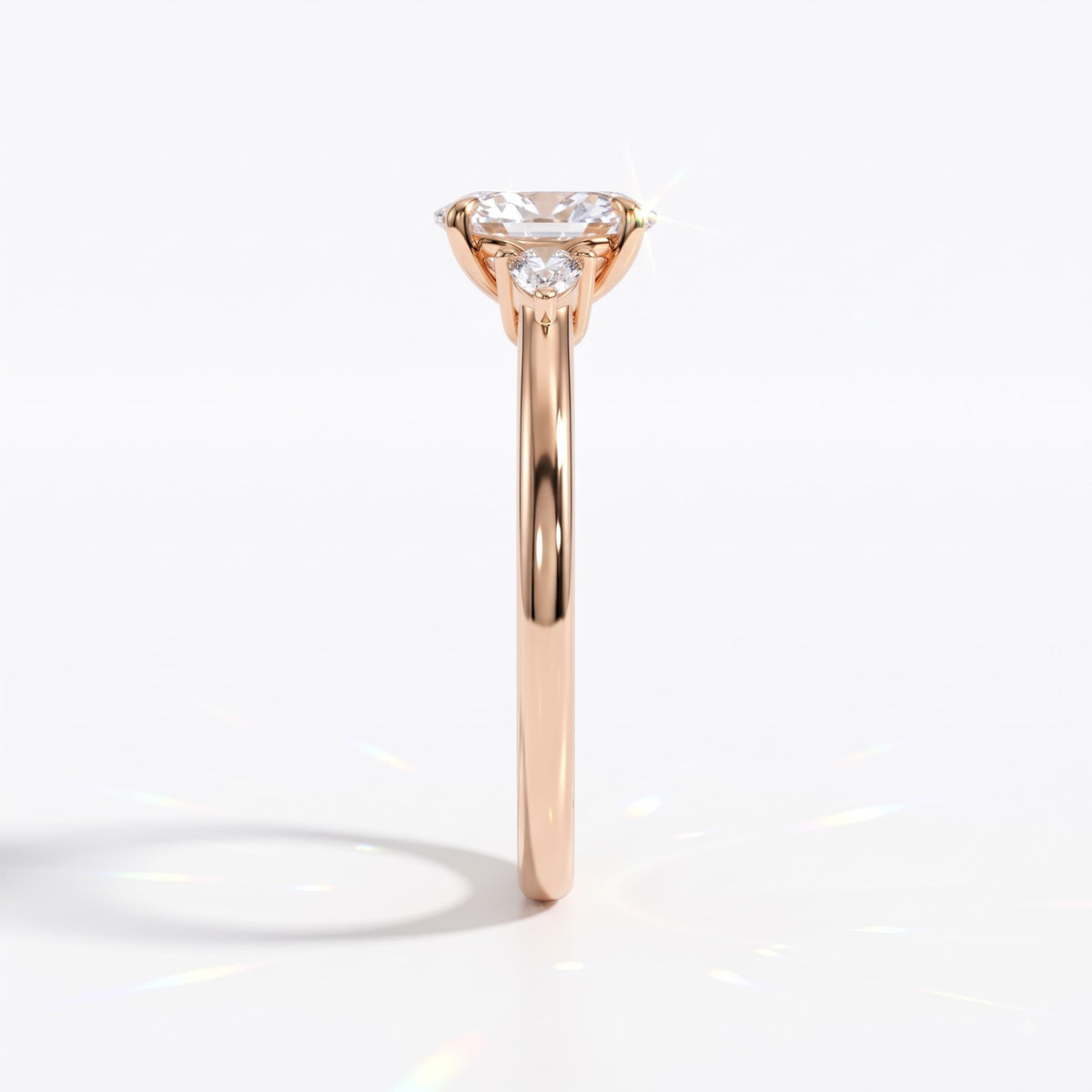 Oval cut lab-grown diamond three-stone engagement ring with pear side stones in 14K (585) rose gold, side view 