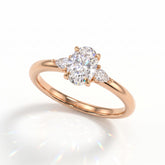 Oval cut lab-grown diamond three-stone engagement ring with pear side stones in 14K (585) rose gold, angled view 