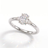 Oval cut lab-grown diamond three-stone engagement ring with pear side stones in 18K (750) white gold, angled view 