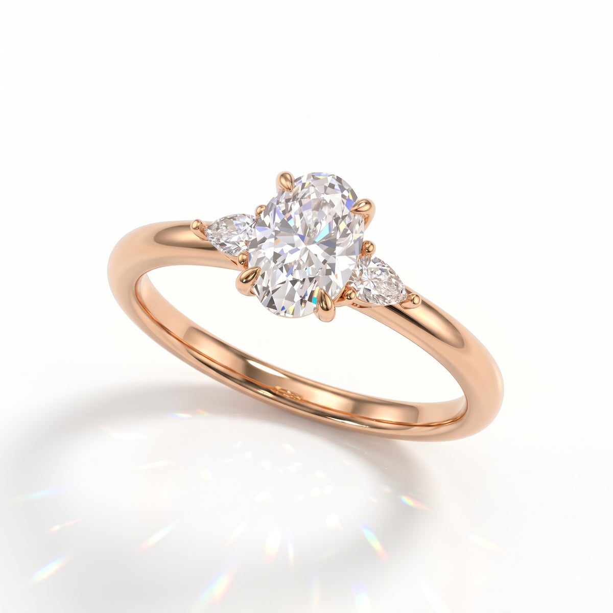 Oval cut lab-grown diamond three-stone engagement ring with pear side stones in 18K (750) rose gold, angled view 
