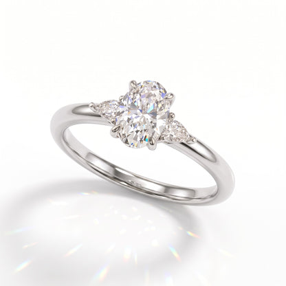 Oval cut lab-grown diamond three-stone engagement ring with pear side stones in 950 platinum, angled view 