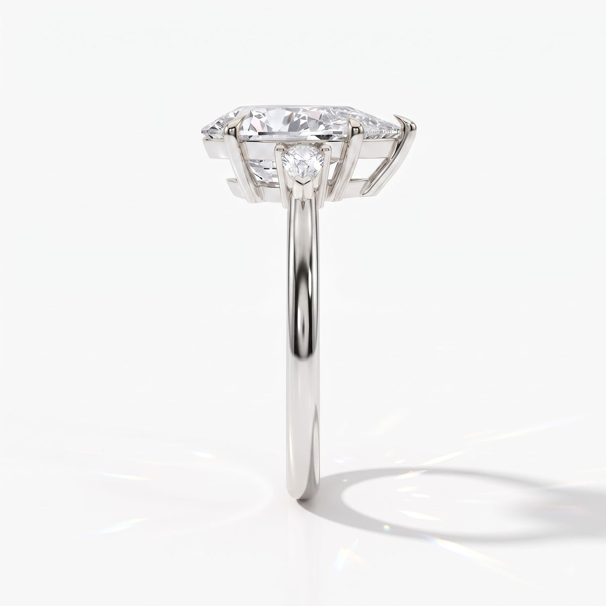 Pear cut lab-grown diamond three-stone engagement ring with pear side stones in 950 platinum, side view 