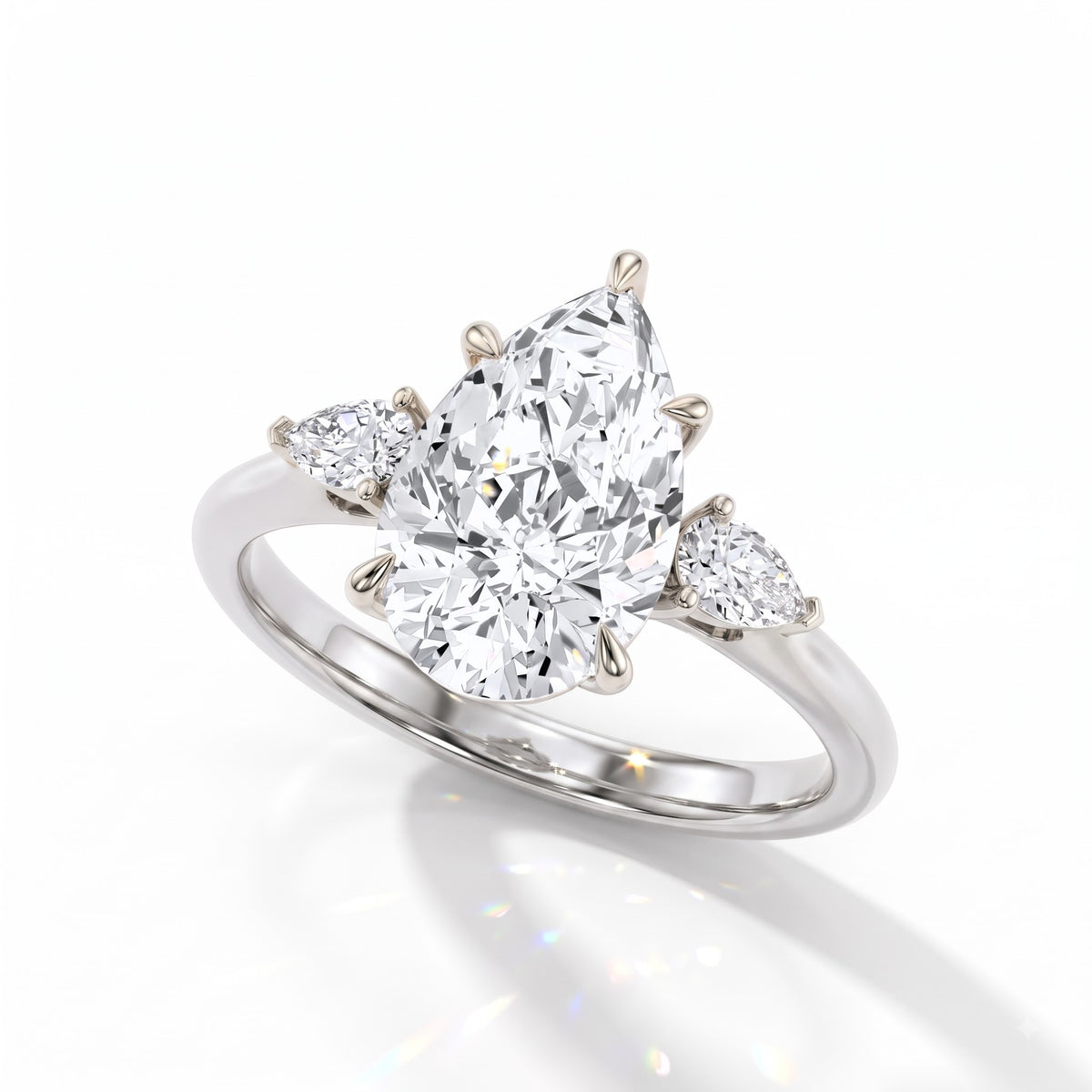 Pear cut lab-grown diamond three-stone engagement ring with pear side stones in 950 platinum, angled view 