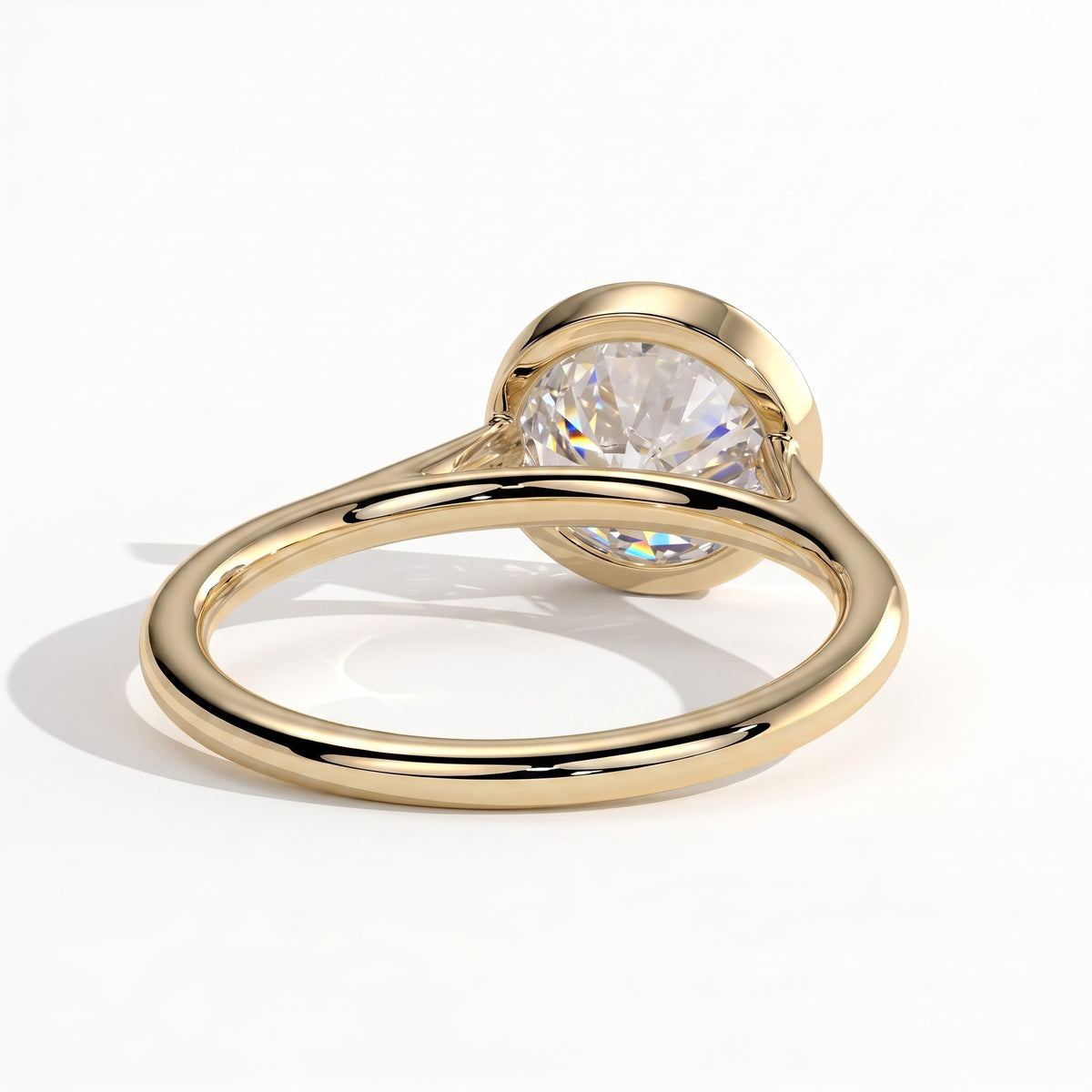 Round lab-grown diamond bezel-set solitaire engagement ring in 14K (585) yellow gold, on white background 
