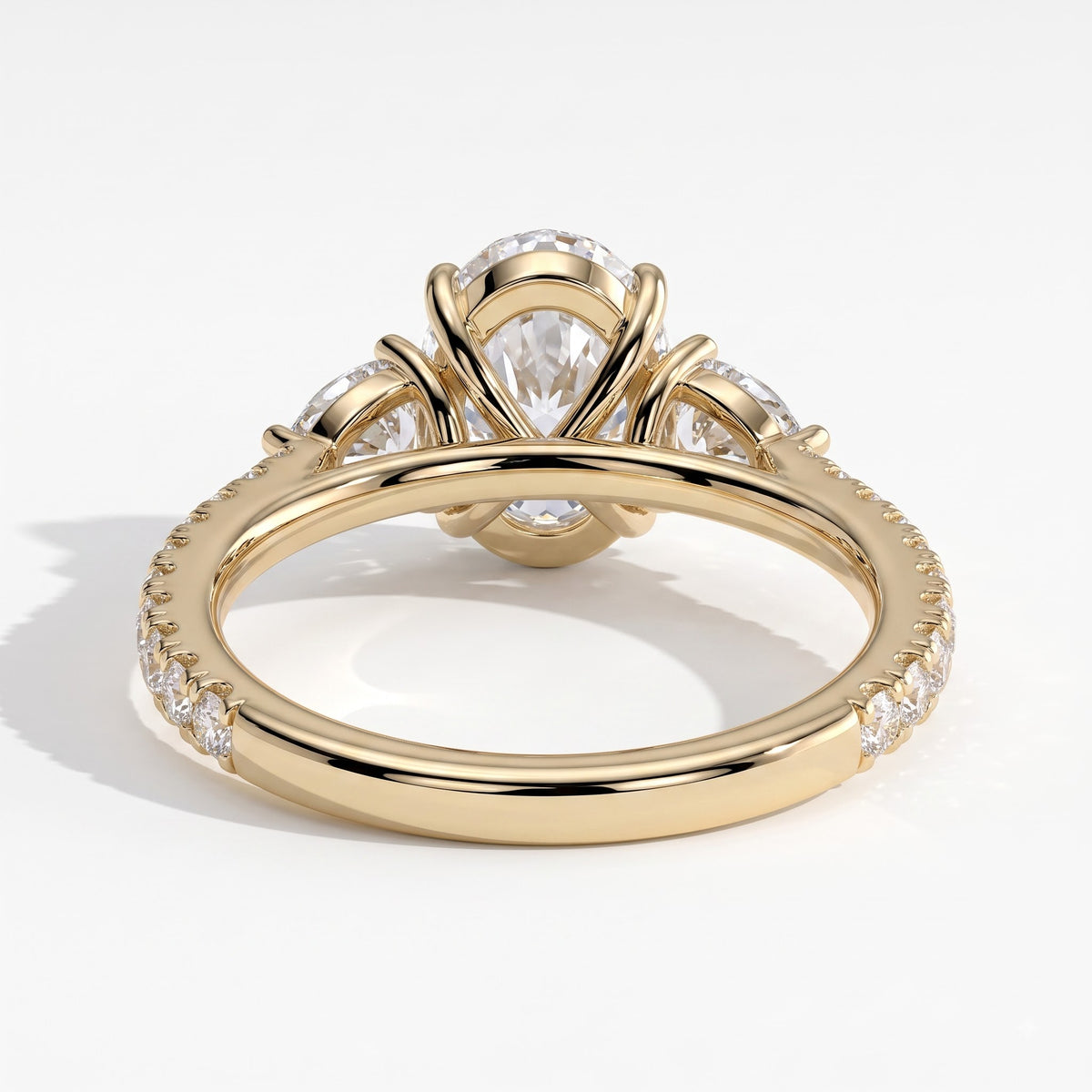 Oval lab-grown diamond three-stone engagement ring in 14K (585) yellow gold, on white background 
