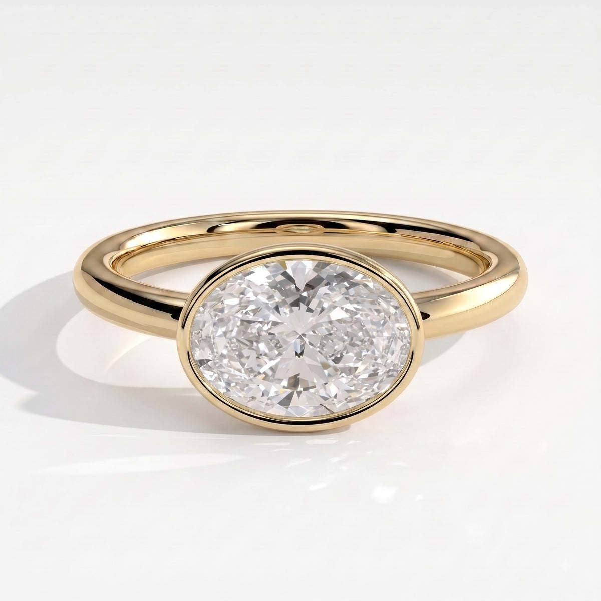 Oval lab-grown diamond bezel-set east-west solitaire engagement ring in 18K (750) yellow gold, front view 