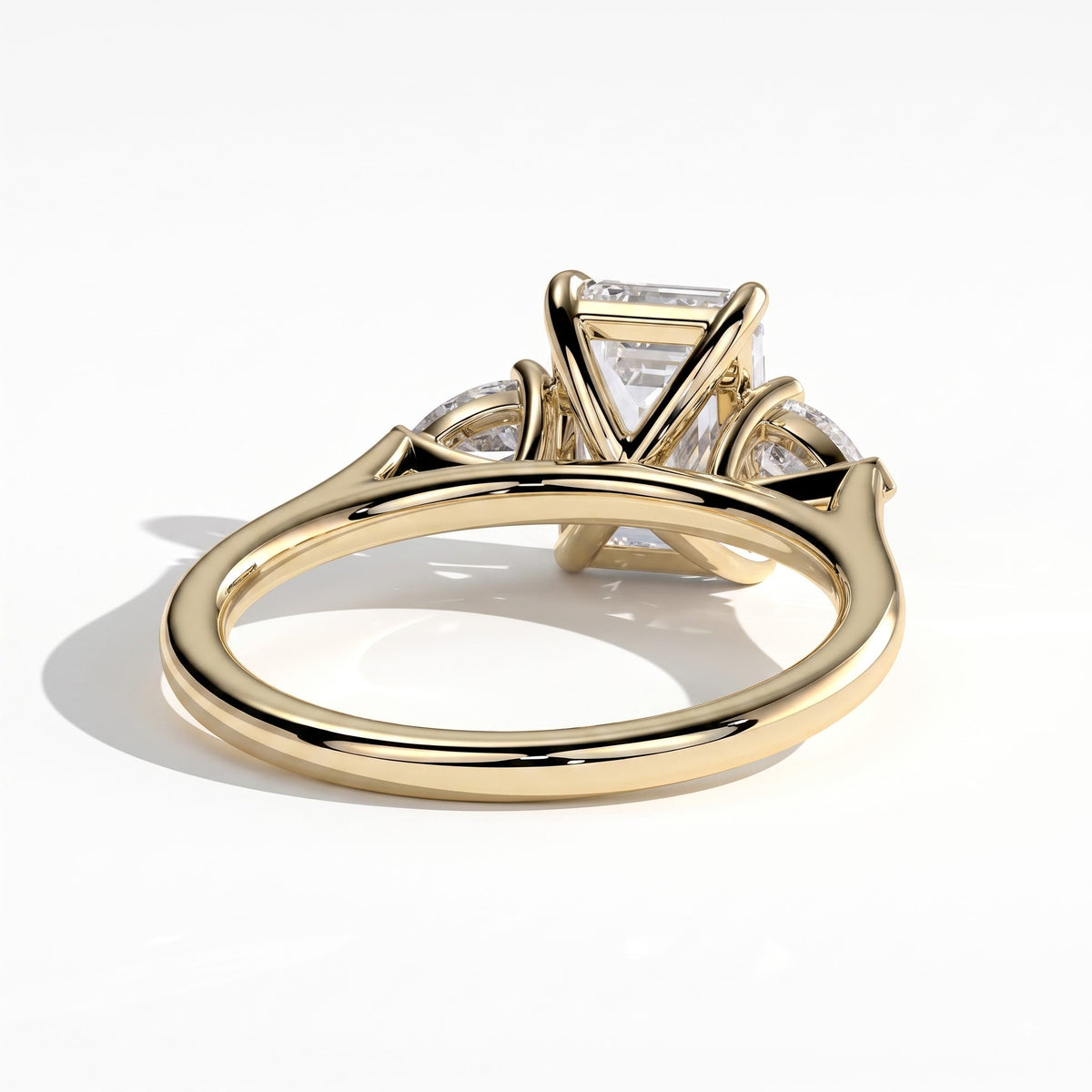 Emerald lab-grown diamond three-stone engagement ring in 14K (585) yellow gold, on white background 