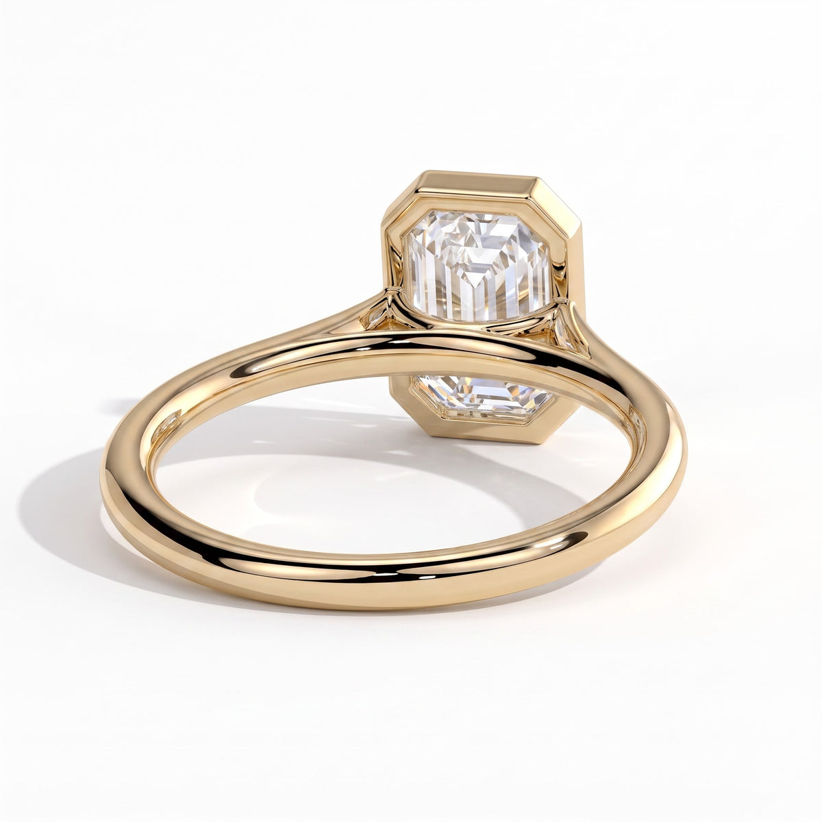 Emerald lab-grown diamond bezel-set solitaire engagement ring in 18K (750) yellow gold, on white background 