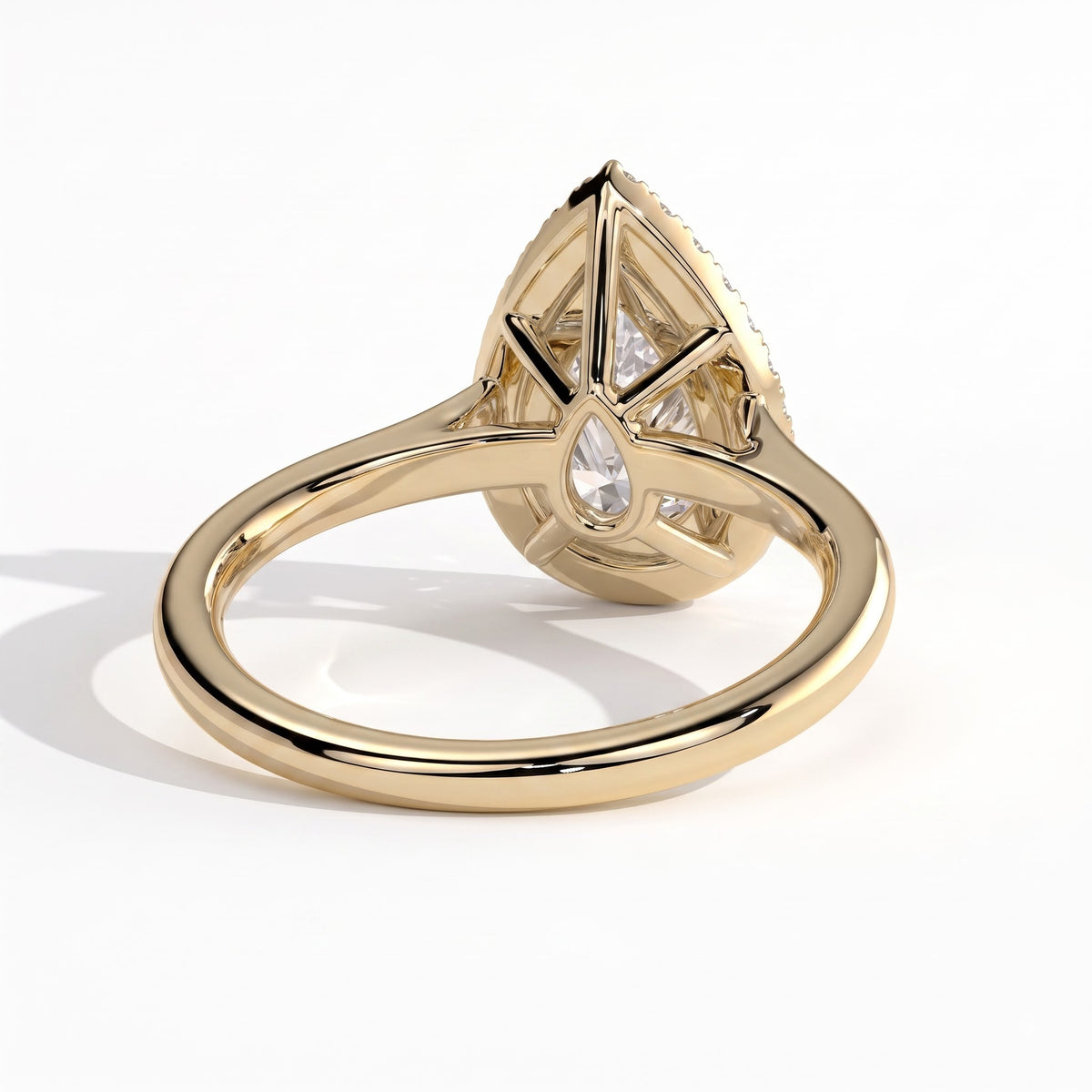 Pear lab-grown diamond halo engagement ring in 14K (585) yellow gold, on white background 