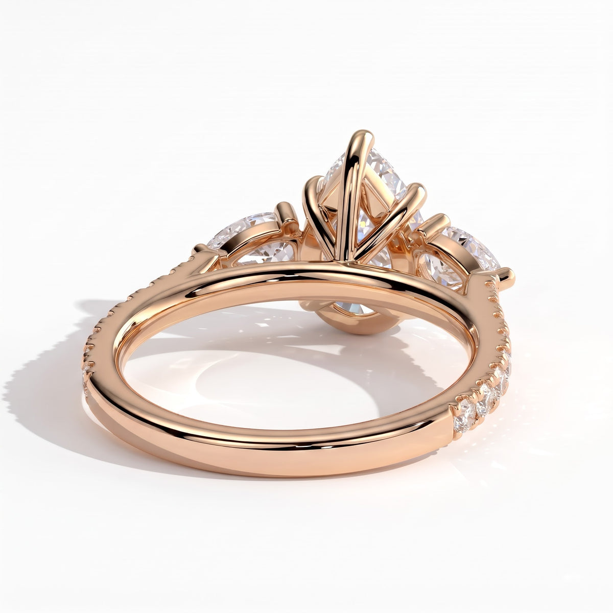 Pear lab-grown diamond three-stone engagement ring in 14K (585) rose gold, on white background 