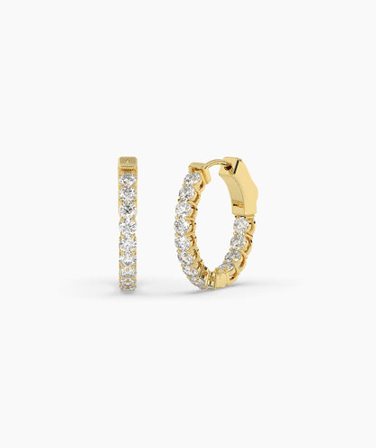 Gold hoop earrings with clear gemstones on a white background. 
