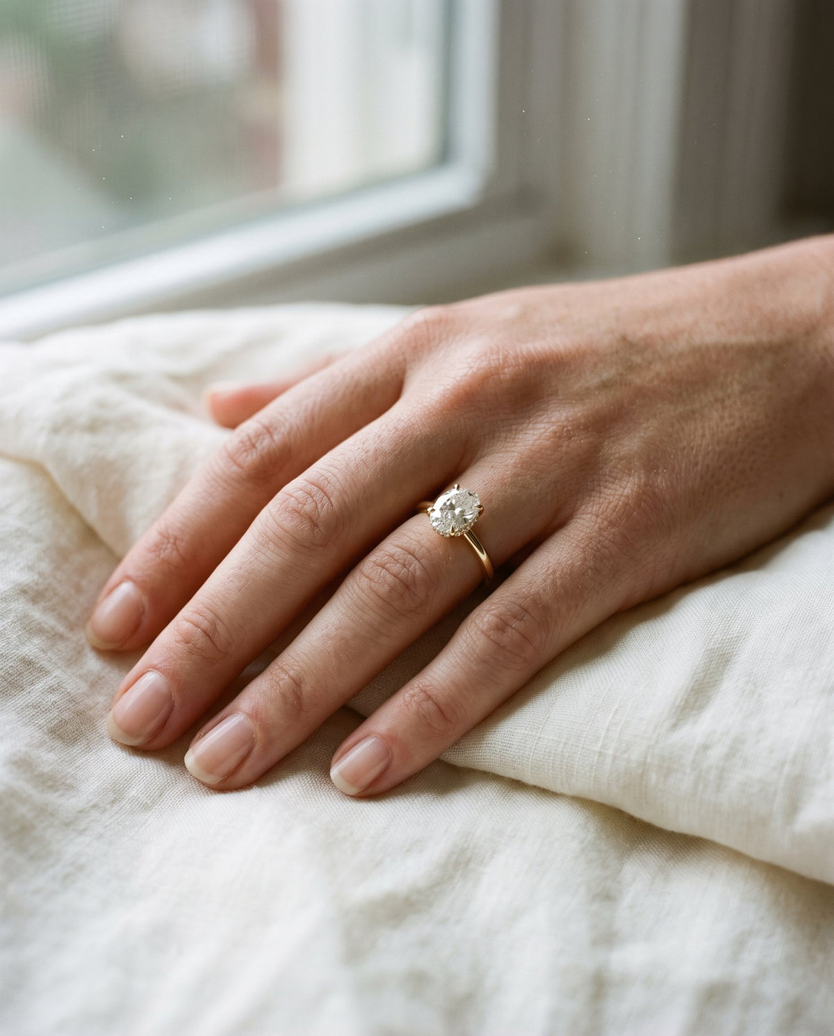 Hidden halo oval engagement ring on the hand | BEUSÉA