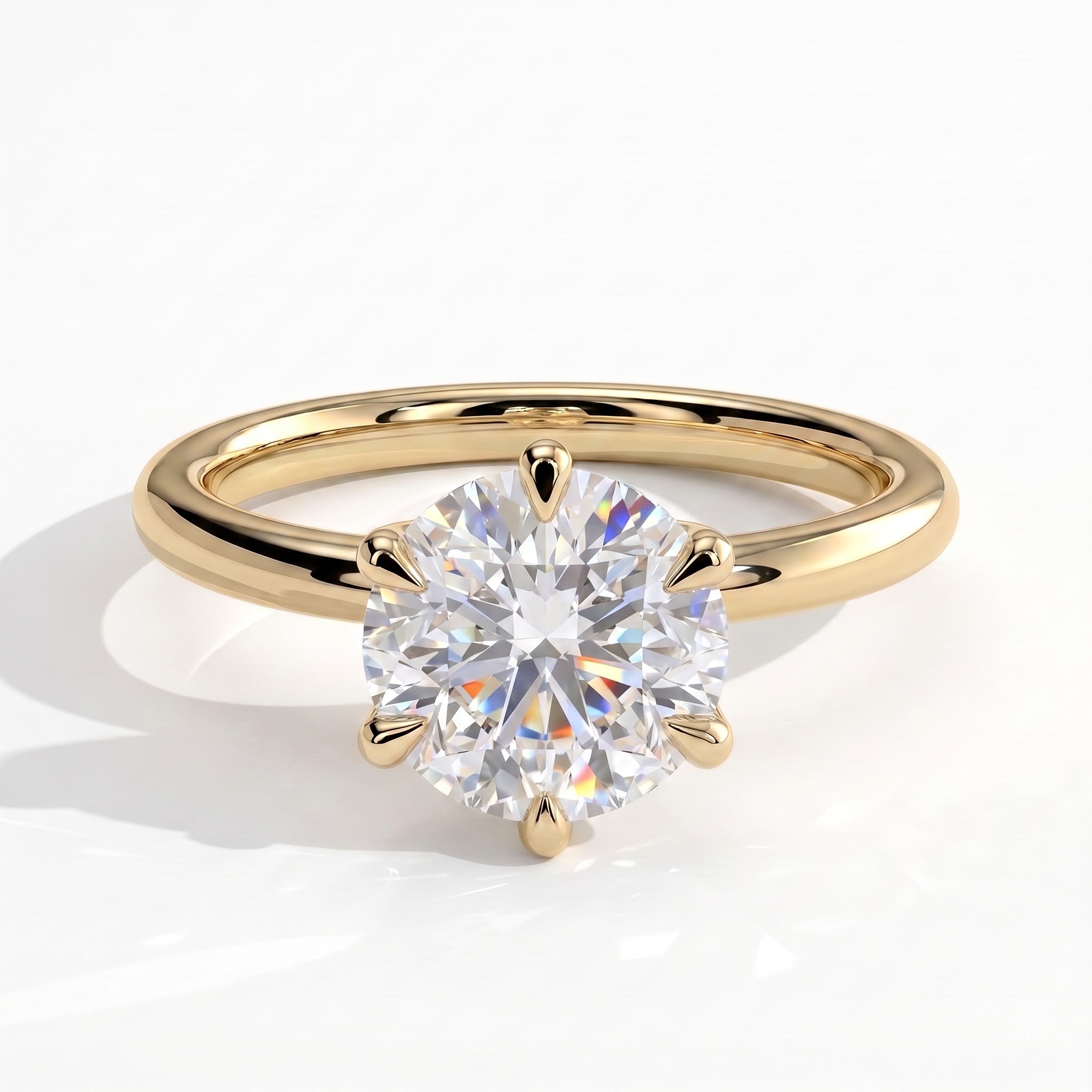 A classic solitaire engagement ring featuring a round brilliant-cut diamond set in a yellow gold four-prong setting, on a polished yellow gold band, shown on a clean white background with a soft shadow. 