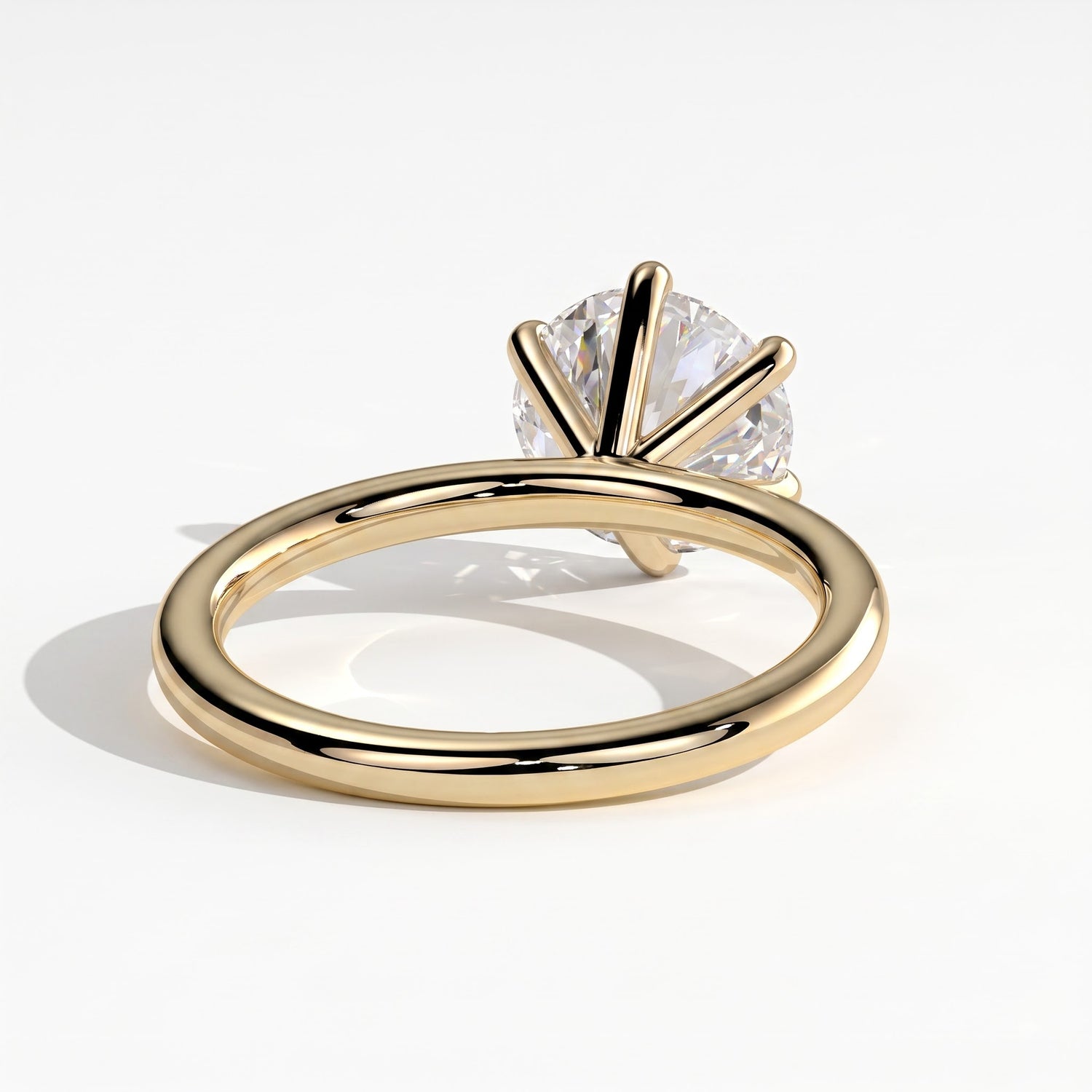 A yellow gold solitaire ring with a round brilliant-cut diamond, shown on a clean white background with a soft shadow. 