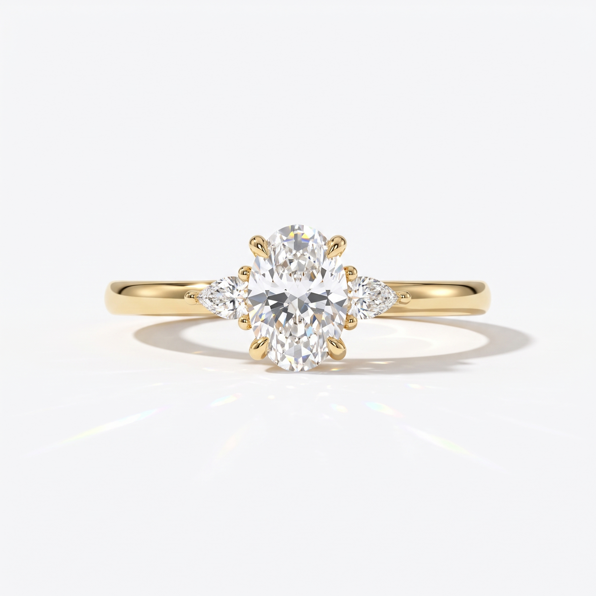 Oval cut lab-grown diamond three-stone engagement ring with pear side stones in 18K (750) yellow gold, front view 