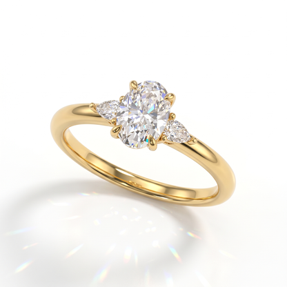 Oval cut lab-grown diamond three-stone engagement ring with pear side stones in 14K (585) yellow gold, angled view 