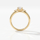 Oval cut lab-grown diamond three-stone engagement ring with pear side stones in 14K (585) yellow gold, upright profile view 