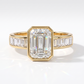 Emerald cut lab-grown diamond bezel engagement ring with channel-set baguette diamonds in 14K (585) yellow gold, front view 