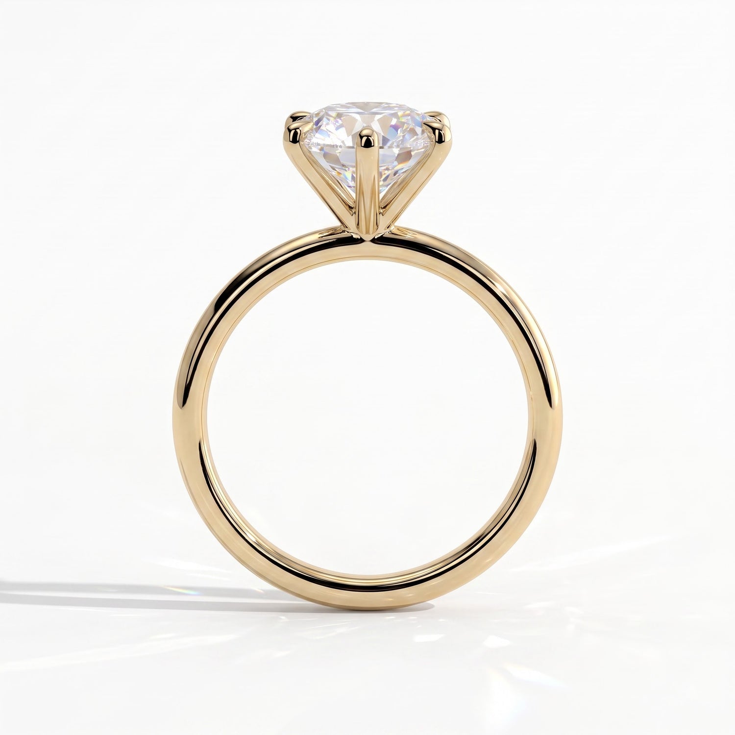 A yellow gold solitaire engagement ring with a round brilliant-cut diamond, shown from a side profile view on a clean white background. 