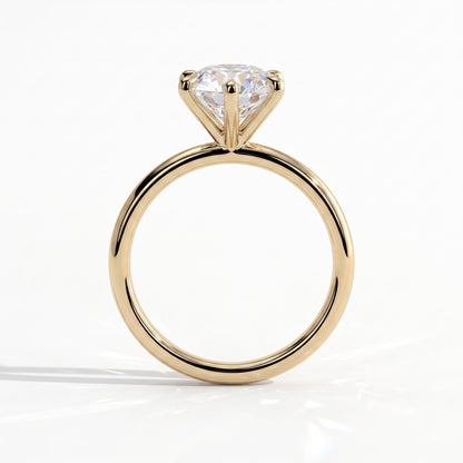 A yellow gold solitaire engagement ring with a round brilliant-cut diamond, shown from a side profile view on a clean white background. 