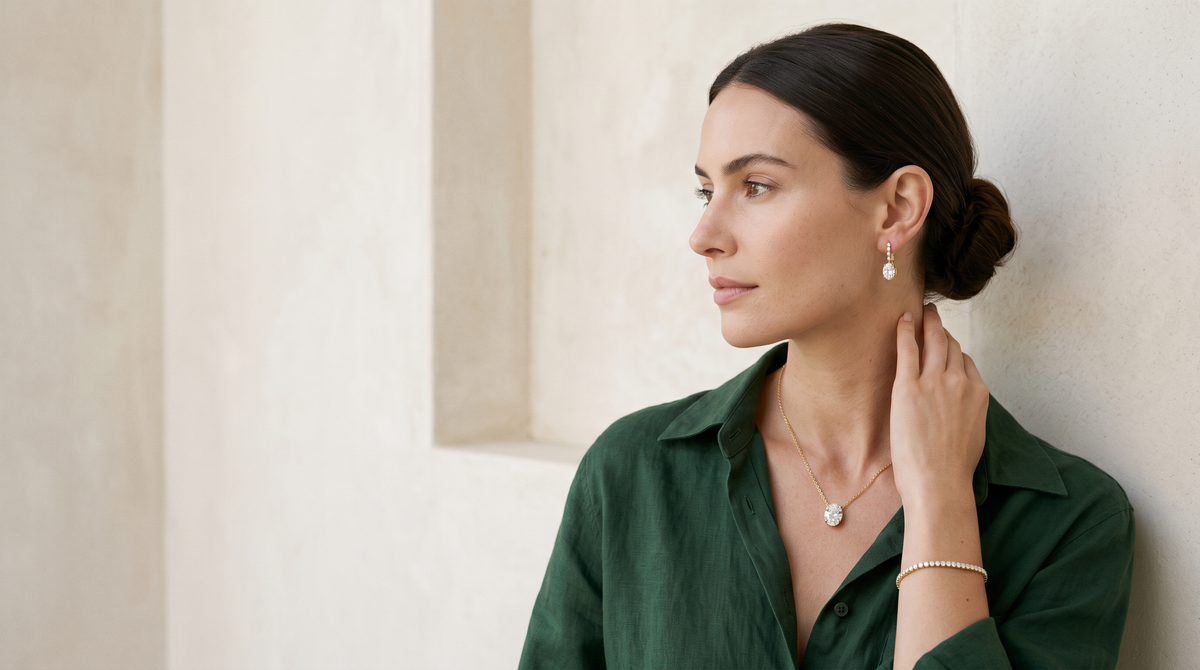 Woman in forest green linen wearing BEUSÉA lab-grown diamond drop earrings, oval pendant necklace and tennis bracelet