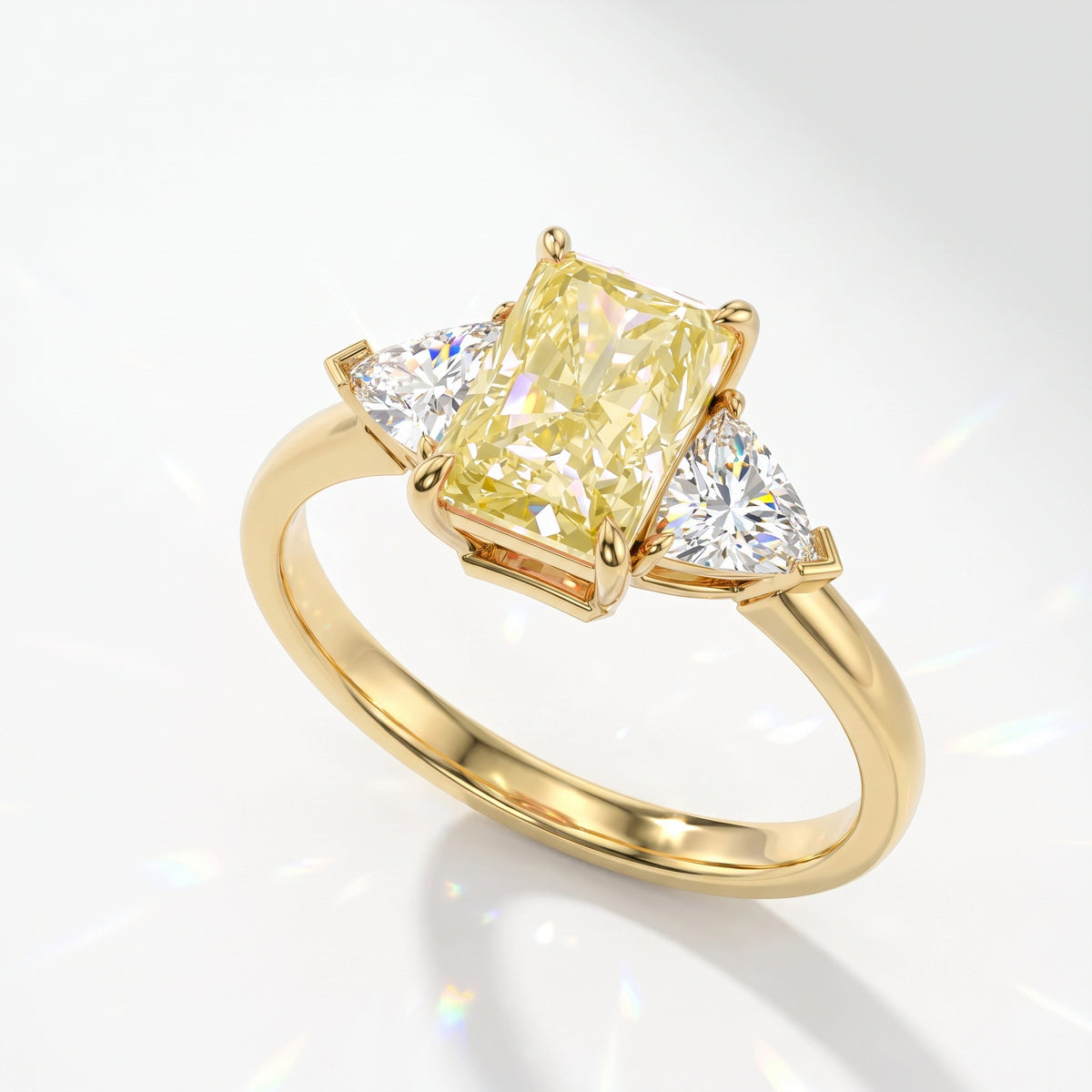 Fancy Vivid Yellow radiant lab-grown diamond three-stone ring with trillion side diamonds in 14K (585) yellow gold, angled view 
