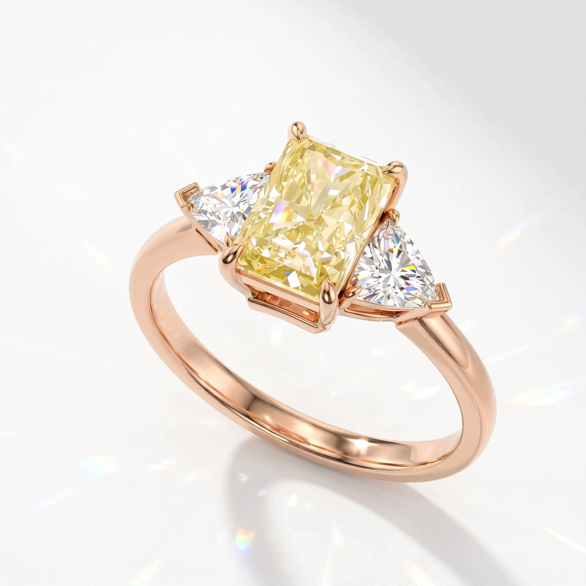 Fancy Vivid Yellow radiant lab-grown diamond three-stone ring with trillion side diamonds in 14K (585) rose gold, angled view 