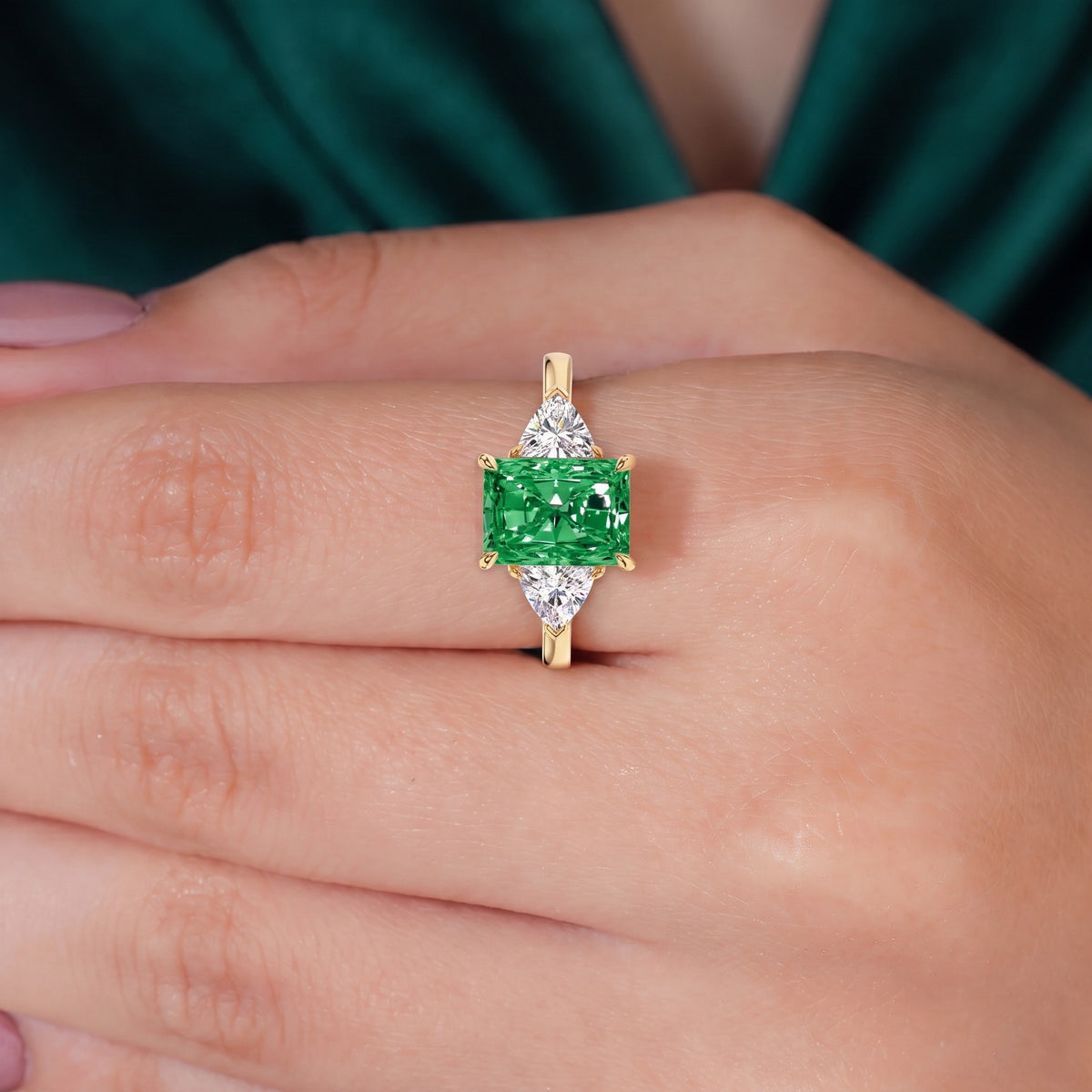 Fancy Vivid Green radiant lab-grown diamond three-stone ring with trillion side diamonds in 950 platinum, worn on finger, on-hand top view 