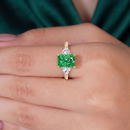 Fancy Vivid Green radiant lab-grown diamond three-stone ring with trillion side diamonds in 18K (750) yellow gold, worn on finger, on-hand top view 