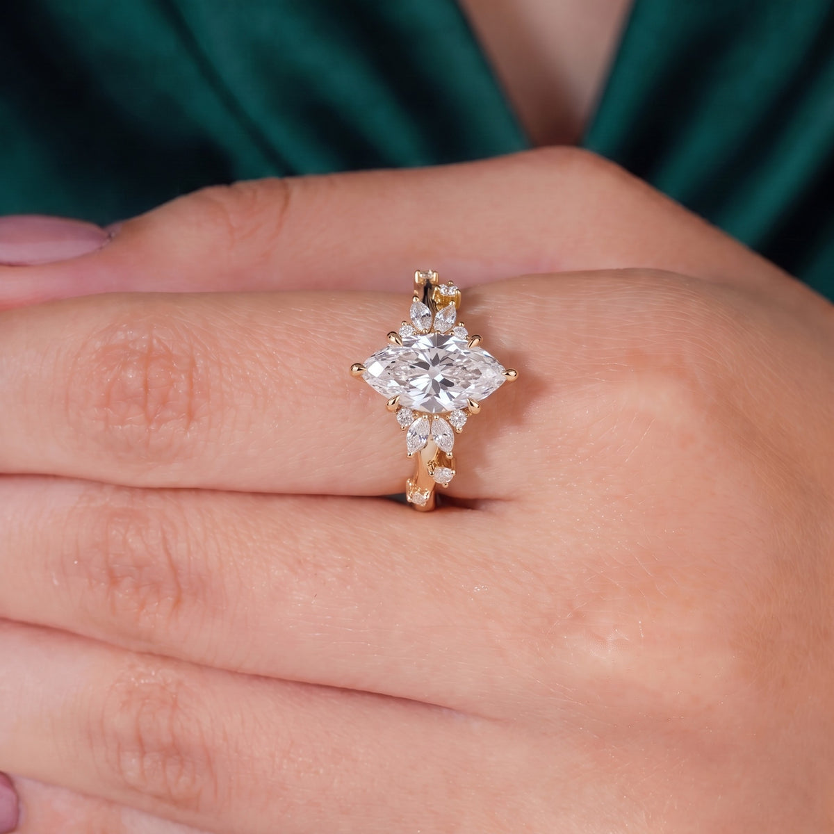 Marquise cut lab-grown diamond cluster engagement ring with marquise and round leaf accents in 14K (585) yellow gold, worn on finger, on-hand top view 