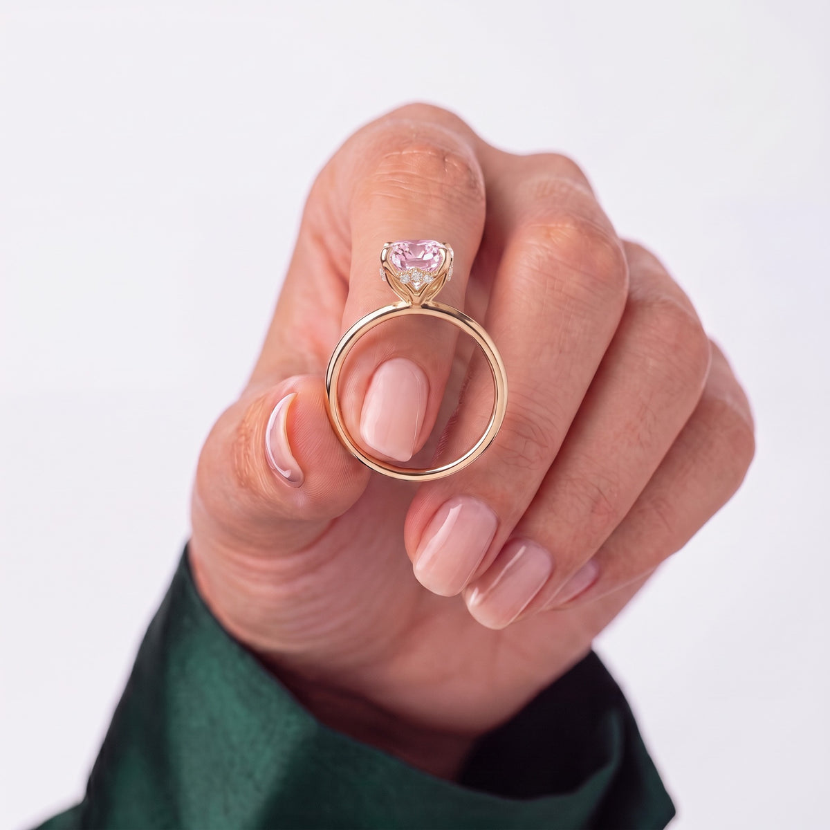 Fancy Vivid Pink oval lab-grown diamond solitaire engagement ring with petal gallery and hidden tiara in 18K (750) rose gold, held in hand for scale 