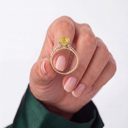 Fancy Vivid Yellow oval lab-grown diamond double claw engagement ring with pavé band and hidden halo in 950 platinum, held in hand for scale 
