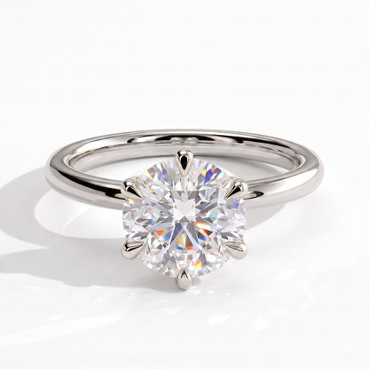 A classic solitaire engagement ring featuring a round brilliant-cut diamond set in a polished white platinum band, shown on a clean white background with a soft shadow. 