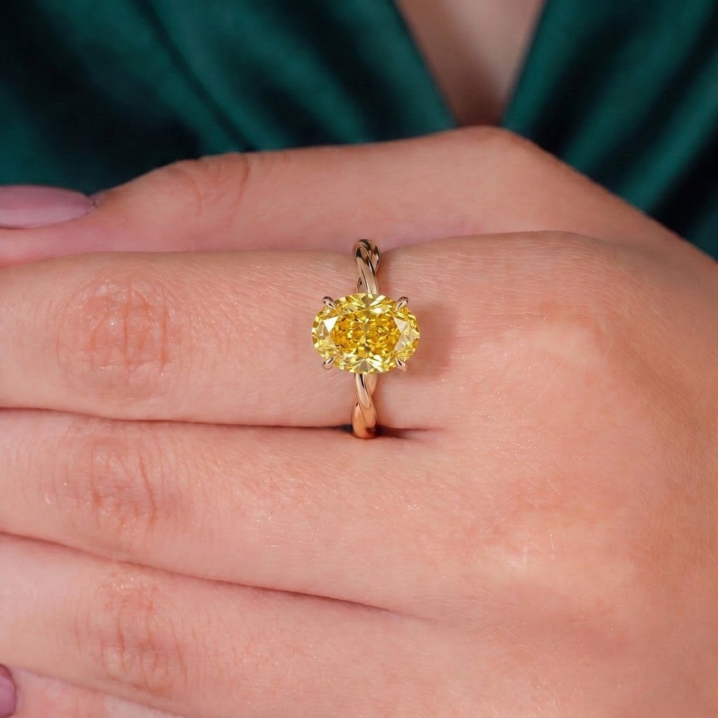 Fancy Vivid Yellow oval lab-grown diamond solitaire engagement ring with twisted band in 14K (585) rose gold, worn on hand 