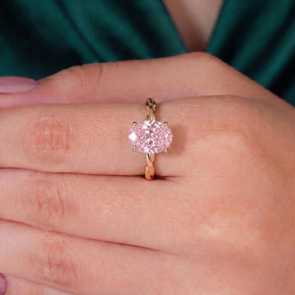 Fancy Vivid Pink oval lab-grown diamond solitaire engagement ring with twisted band in 14K (585) white gold, worn on hand 