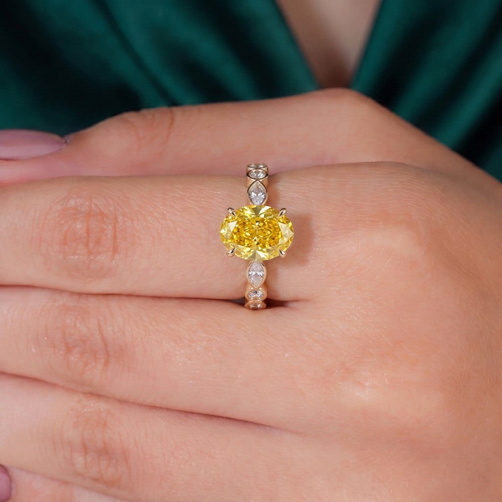 Fancy Vivid Yellow oval lab-grown diamond engagement ring with bezel-set pear and round shoulder accents in 14K (585) white gold, worn on hand 