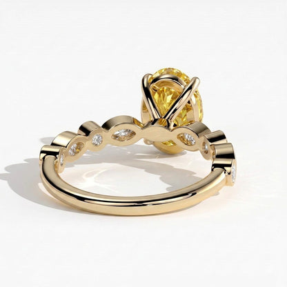 Fancy Vivid Yellow oval lab-grown diamond engagement ring with bezel-set pear and round shoulder accents in 14K (585) yellow gold, detail view of the bezel-set shoulder accents 