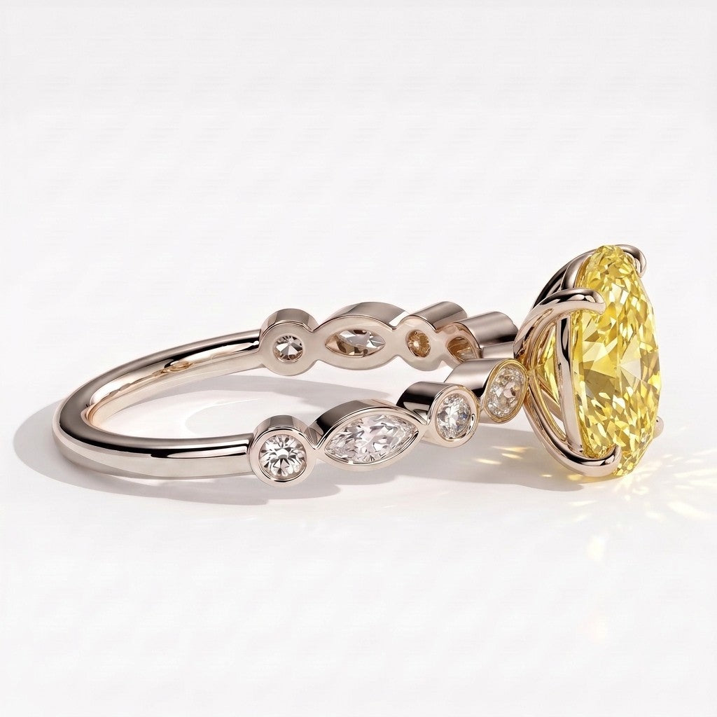 Fancy Vivid Yellow oval lab-grown diamond engagement ring with bezel-set pear and round shoulder accents in 18K (750) white gold, detail view of the bezel-set shoulder accents 