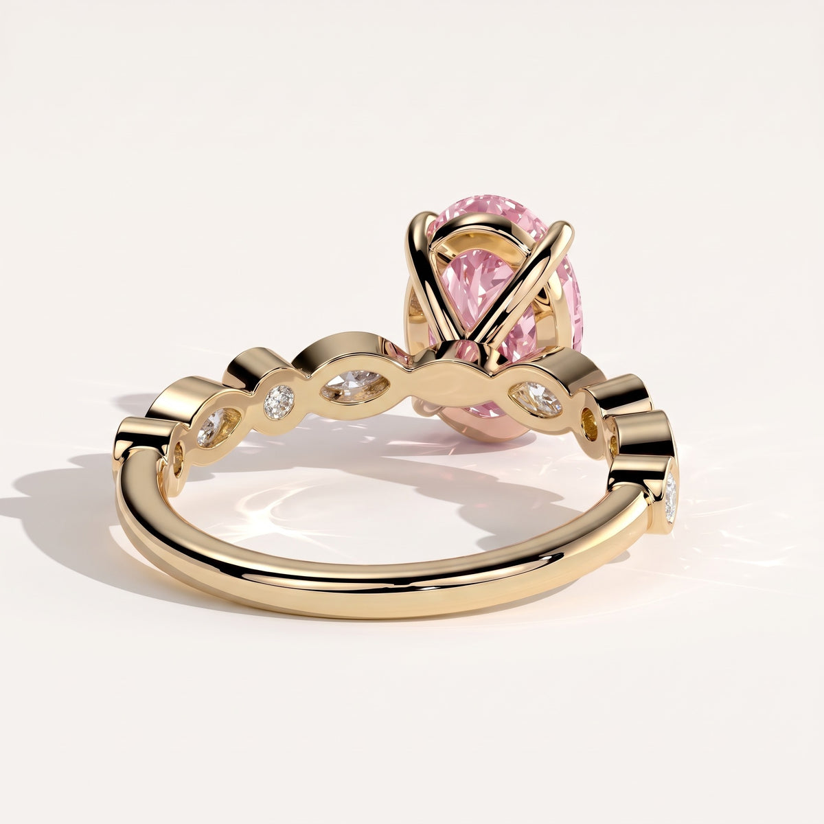 Fancy Vivid Pink oval lab-grown diamond engagement ring with bezel-set pear and round shoulder accents in 14K (585) yellow gold, detail view of the bezel-set shoulder accents 