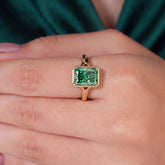 Fancy Vivid Green radiant lab-grown diamond bezel ring in 14K (585) yellow gold, worn on finger, on-hand top view 